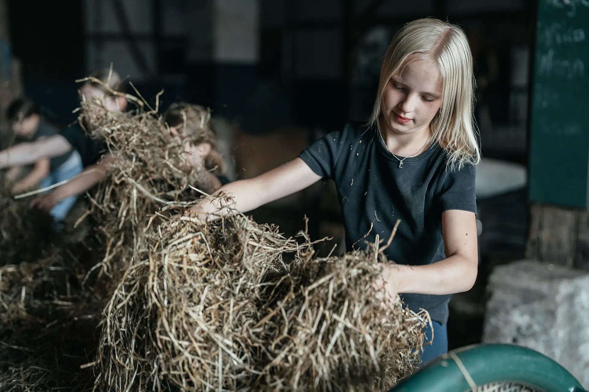 Ein Mädchen verteilt Heu für einen Pferdestall auf Ponyhof Mormann