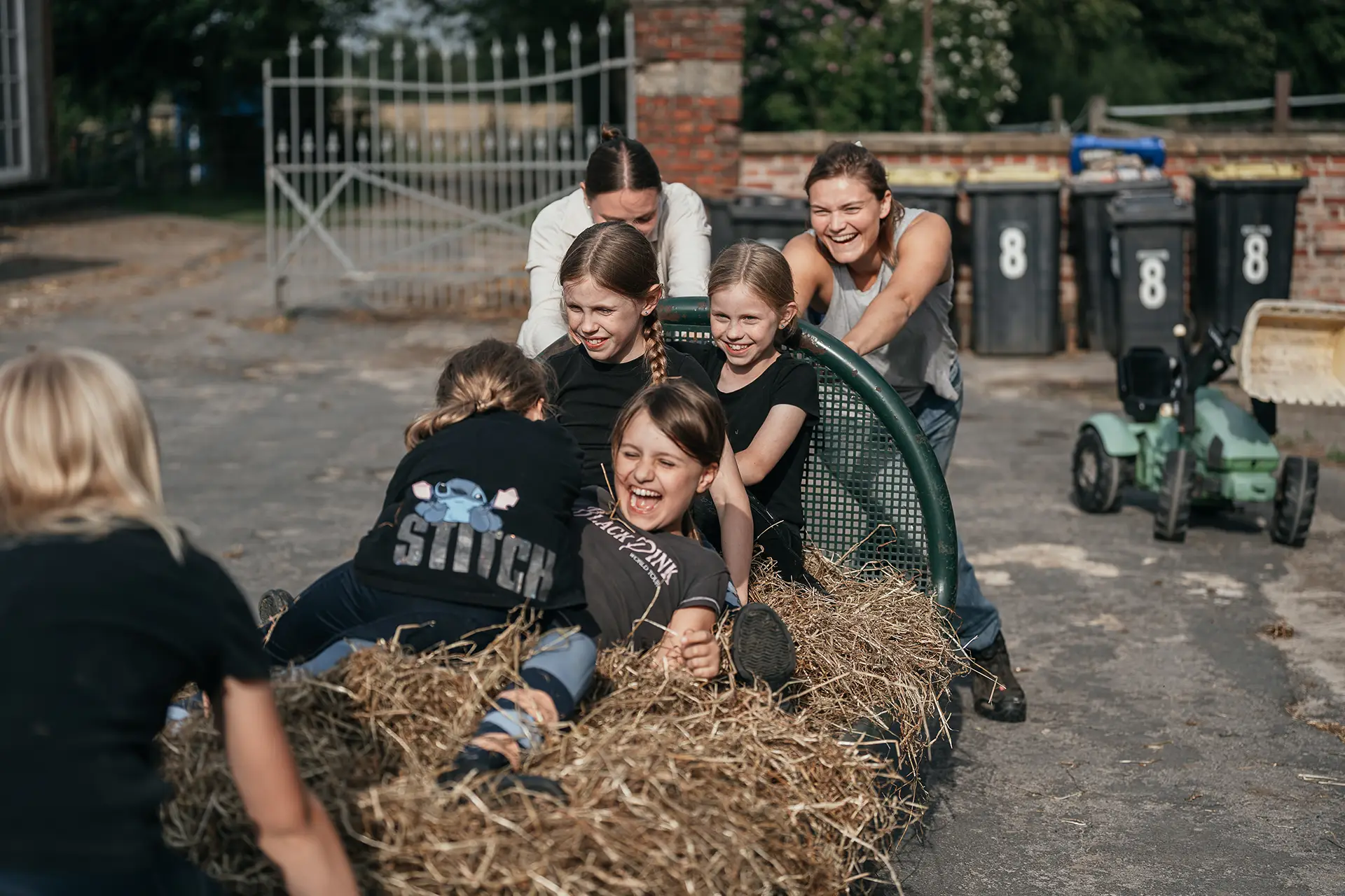 Kinder spielen freudig auf dem Heuwagen draußen auf dem Ponyhof Mormann