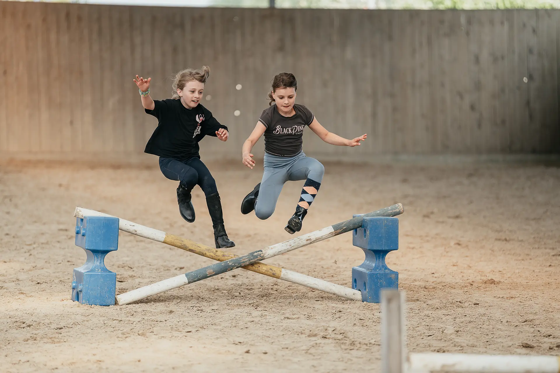 Mädchen spielen und springen in der Reithalle auf dem Sand