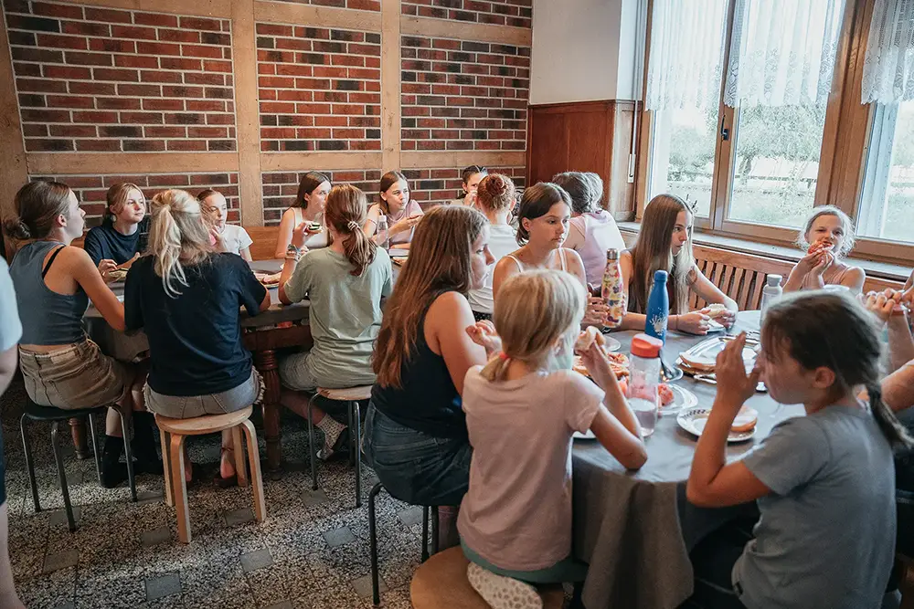 Eine große Gruppe Kinder essen gemeinsam im Speiseraum auf dem Hof Mormann
