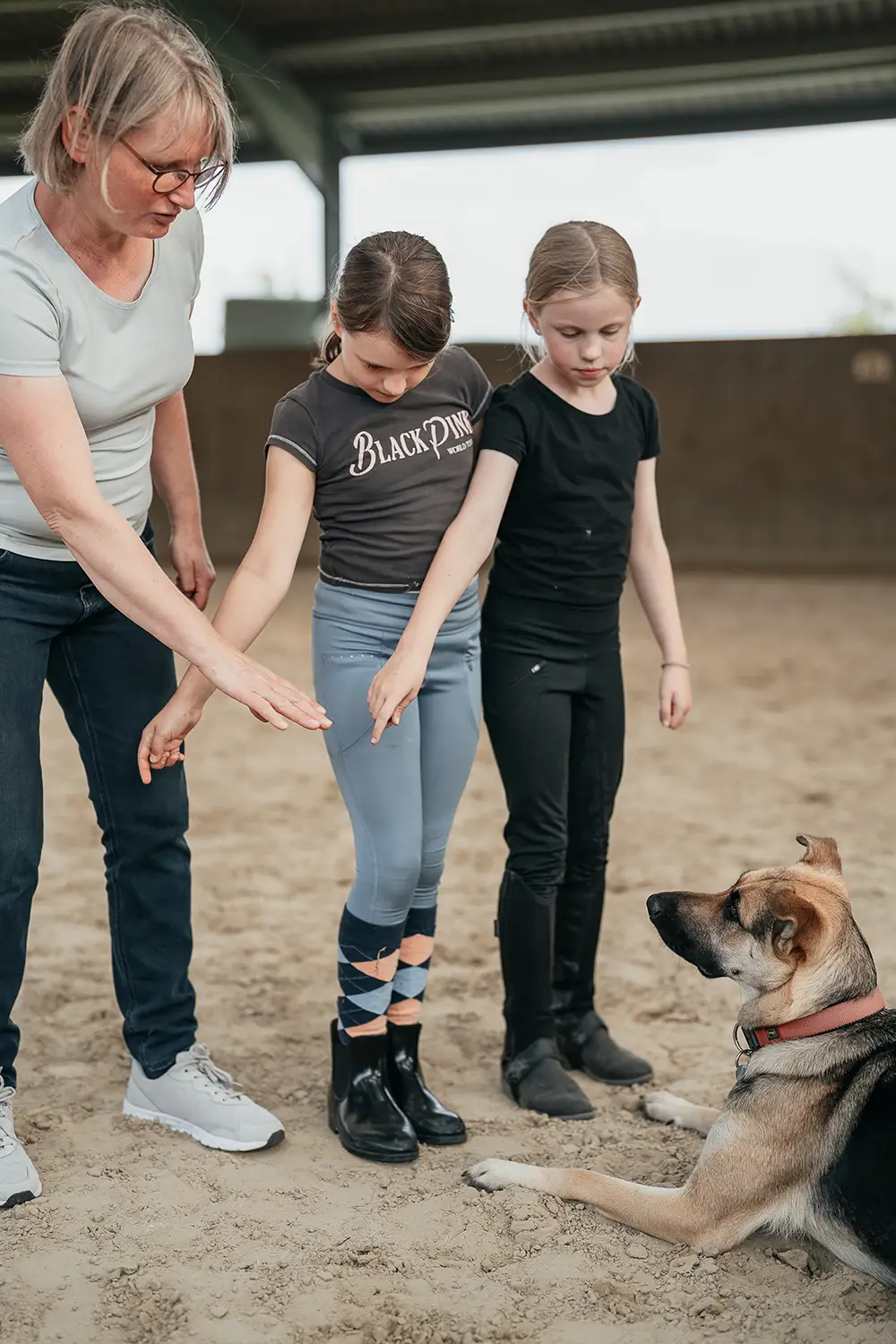 Uta Mormann und zwei Mädchen trainieren mit dem Hund von Hof Mormann in der Reithalle